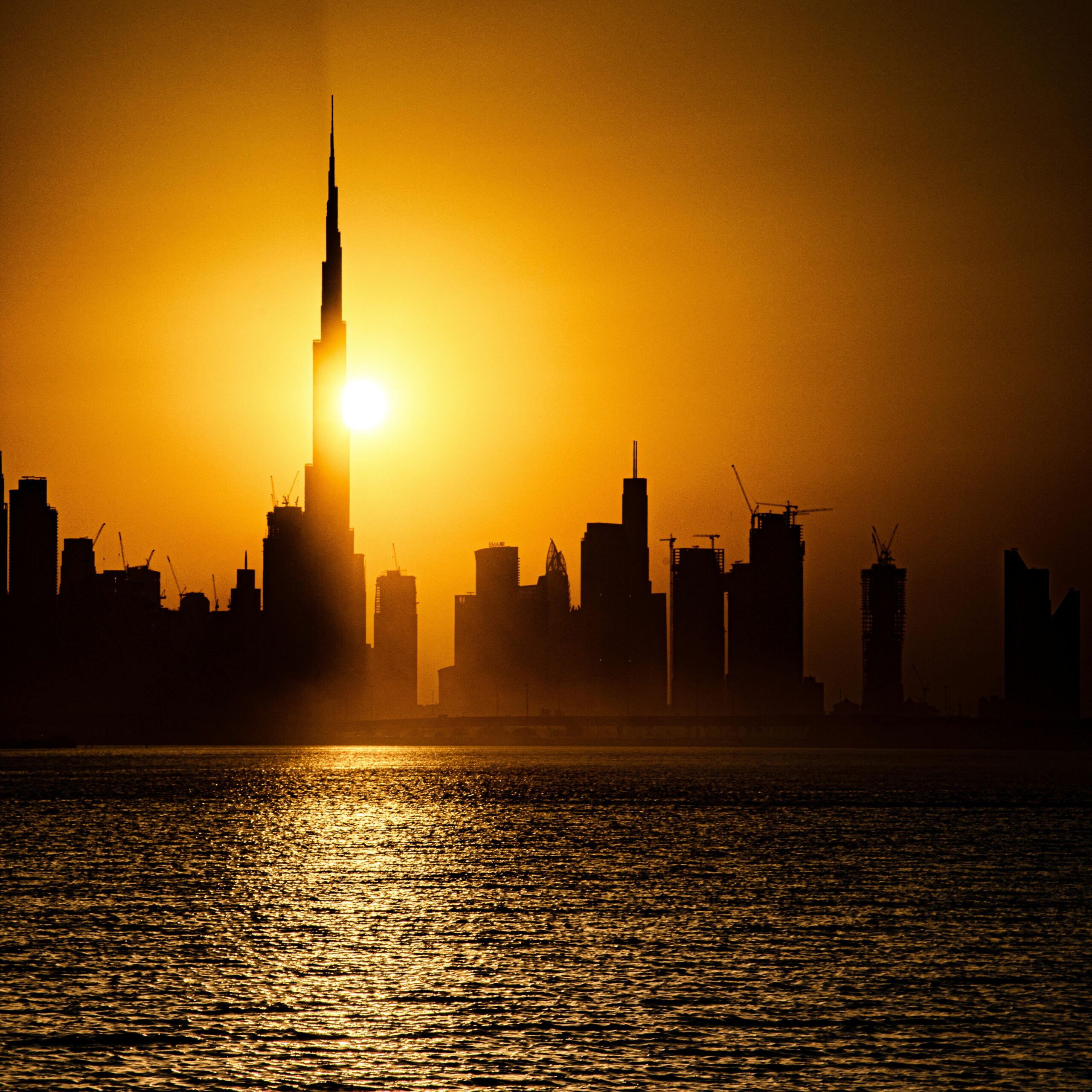 Stunning sunset view of Dubai skyline featuring the iconic Burj Khalifa silhouetted against the golden sky.