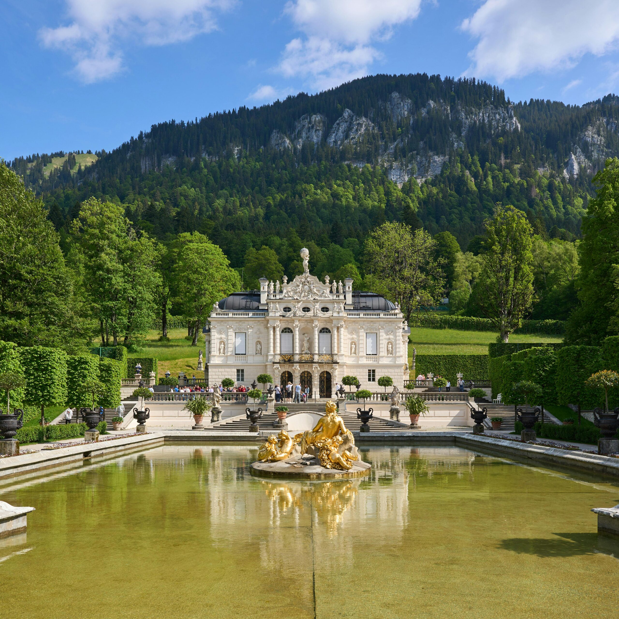 Linderhof Palace with lush gardens and scenic mountain backdrop in Bavaria, Germany.